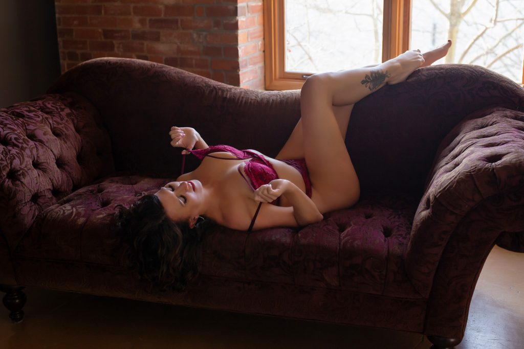 Woman modelling red lingerie on couch.