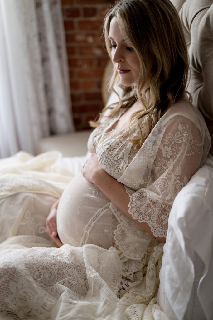 woman sitting in bed posing for maternity shoot