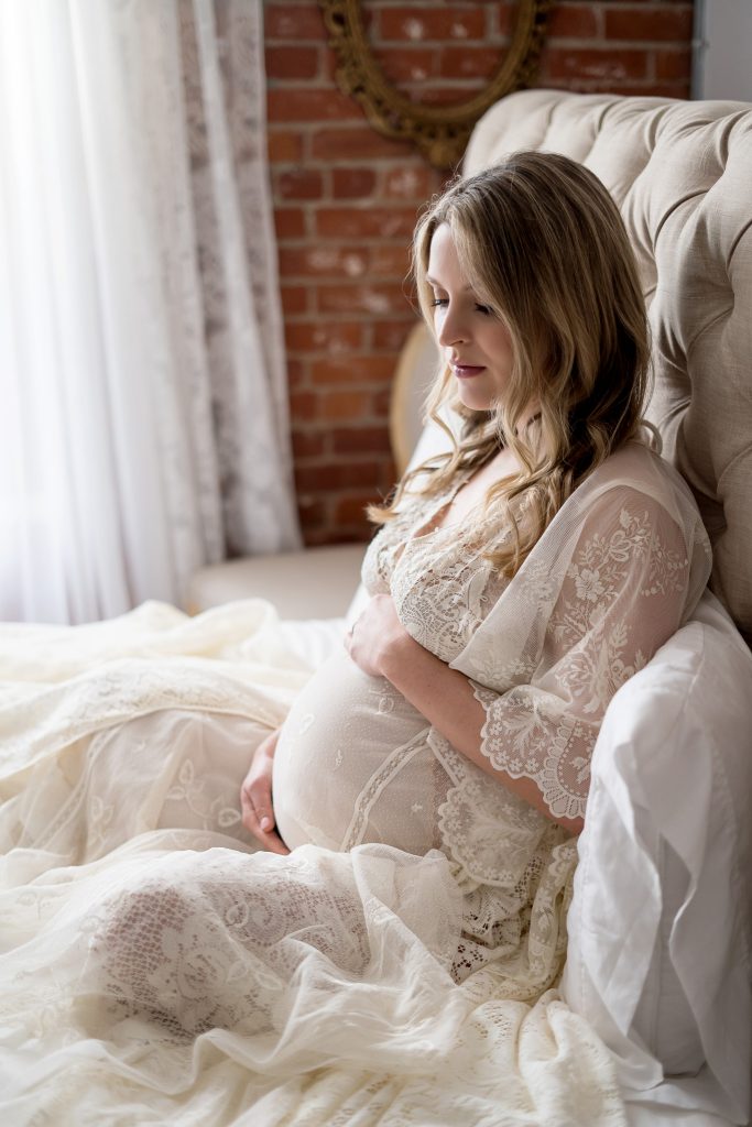 woman sitting in bed posing for maternity shoot