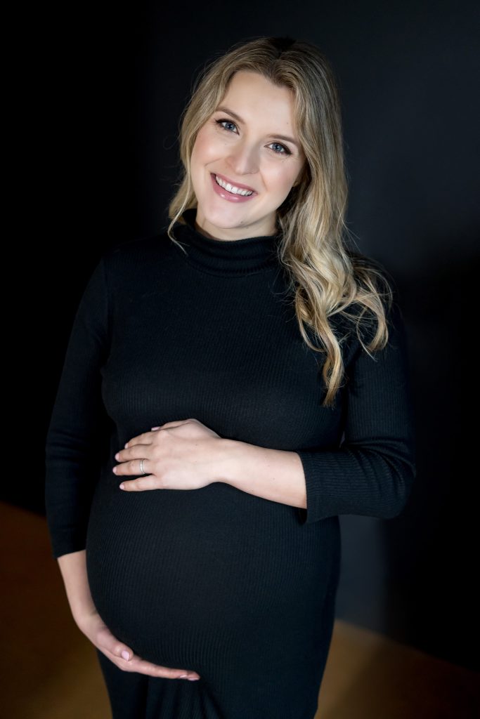 woman holding belly in black dress pregnant