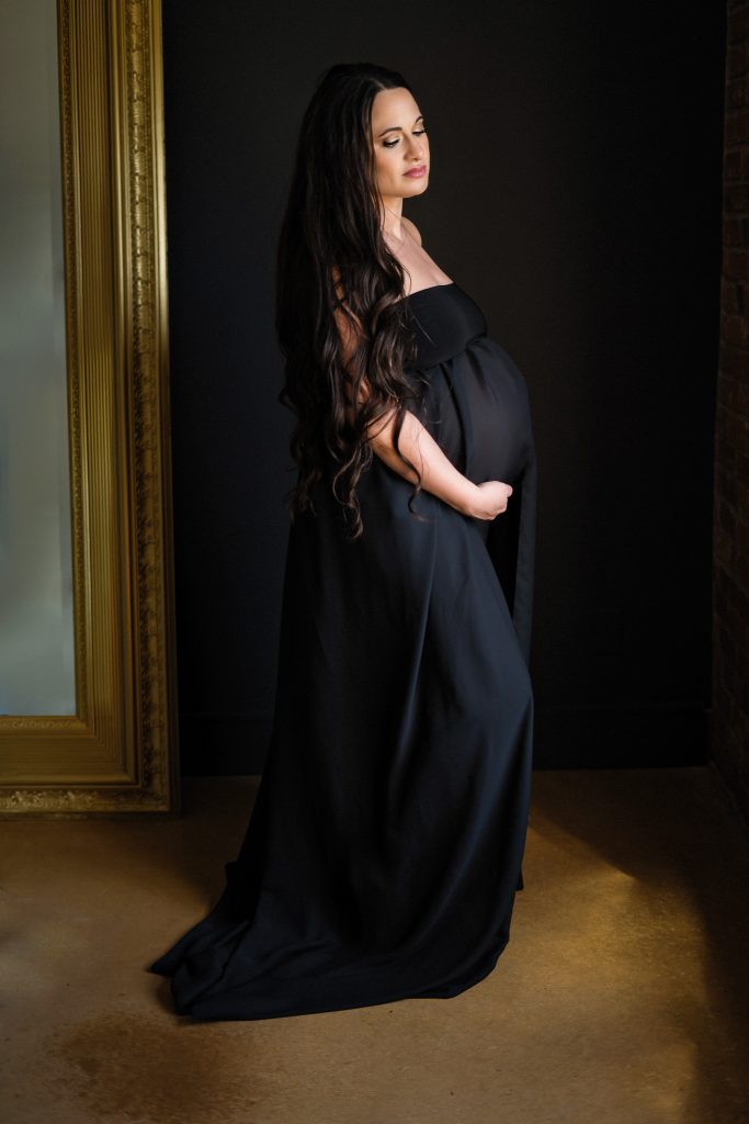 woman posing in black gown for boudoir maternity