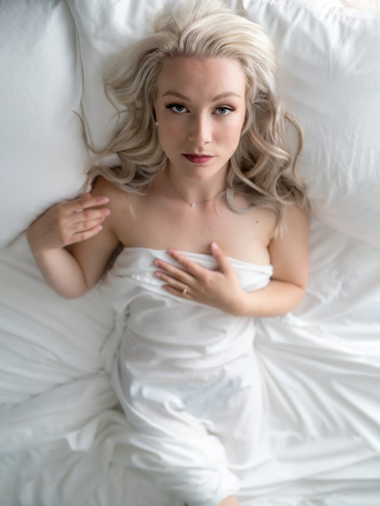 woman lying on bed with white sheet