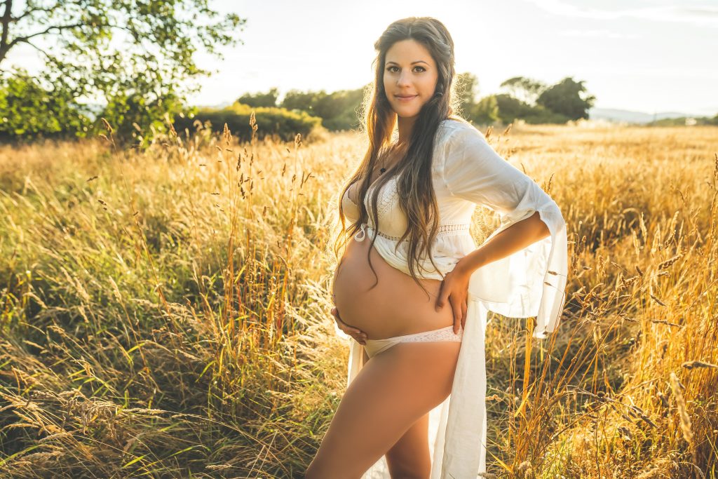 woman posing with belly in field